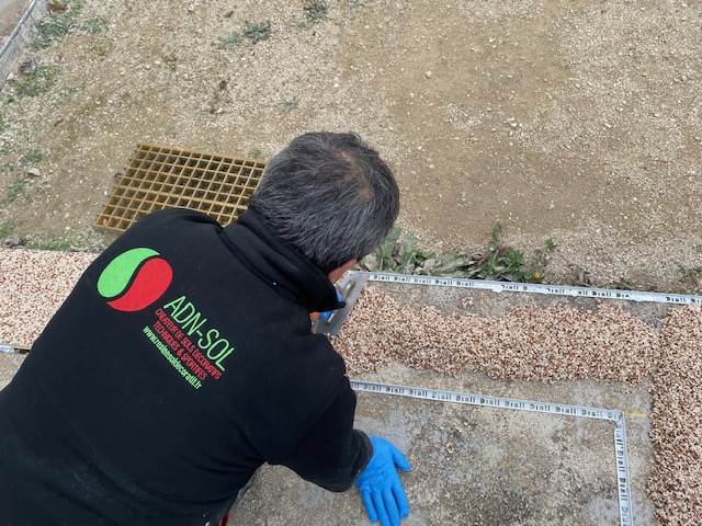 Technicien appliquant la moquette de pierre avec expertise pour un aménagement extérieur de qualité, proposée par ADN-SOL.